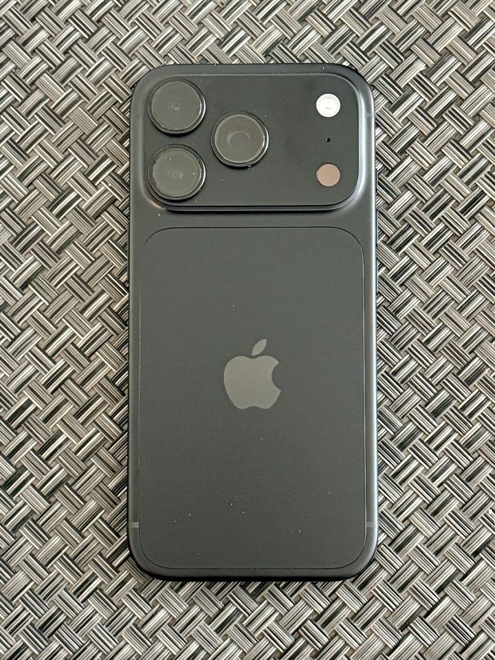 Tył czarnego iPhone’a 18 Pro leżącego na plecionej powierzchni